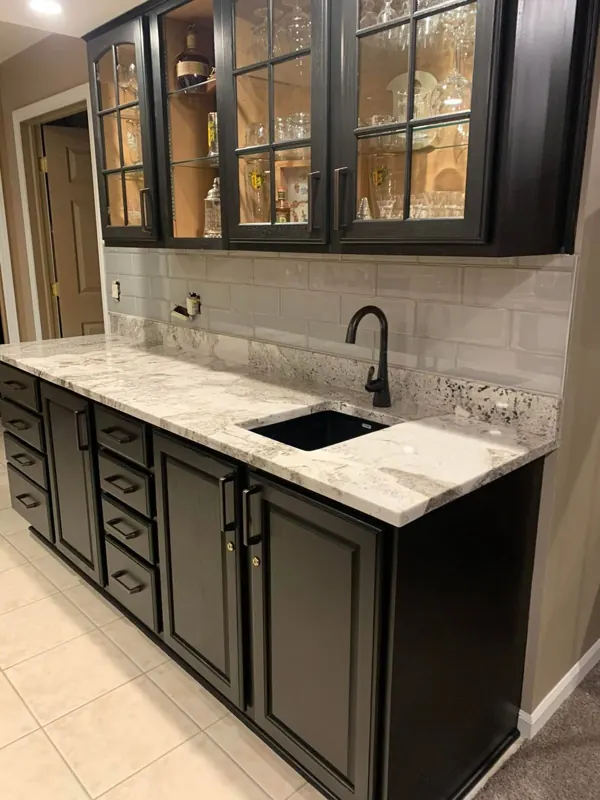 Black cabinets with a white veined countertop and glass uppers